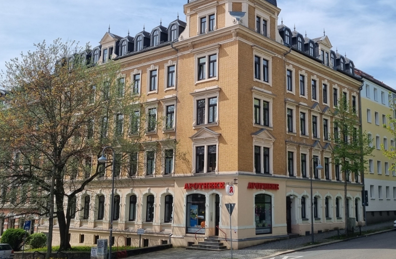 Dieses Bild zeigt ein oranges Etagenwohnhaus an einem hellen Tag unter blauem, bewölktem Himmel.