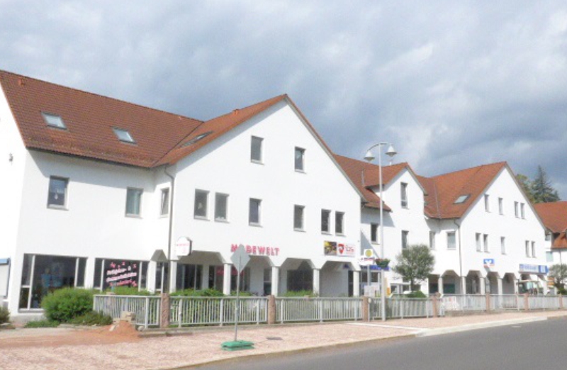 Dieses Bild zeigt ein weißes Etagenwohnhaus in Neukirchen unter bewölktem Himmel.